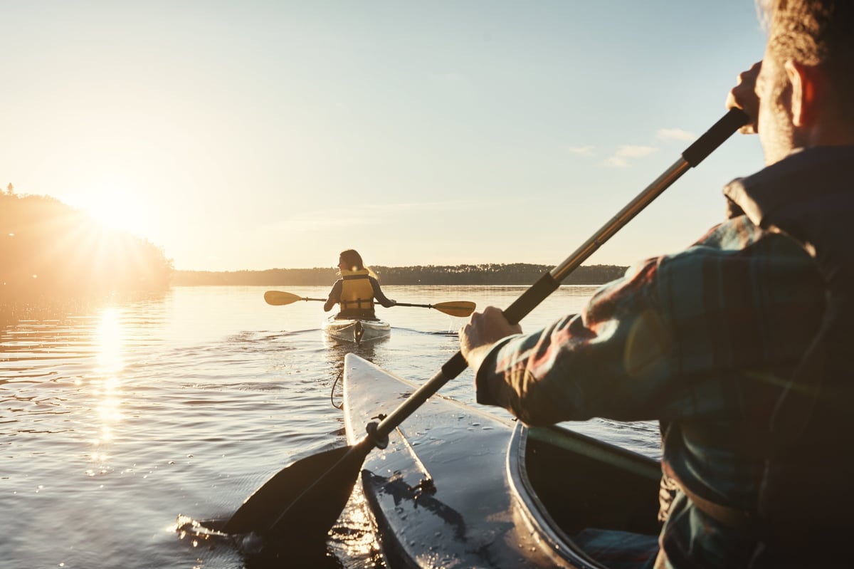 A young couple enjoying a sober weekend kayaking together on a calm lake outdoors